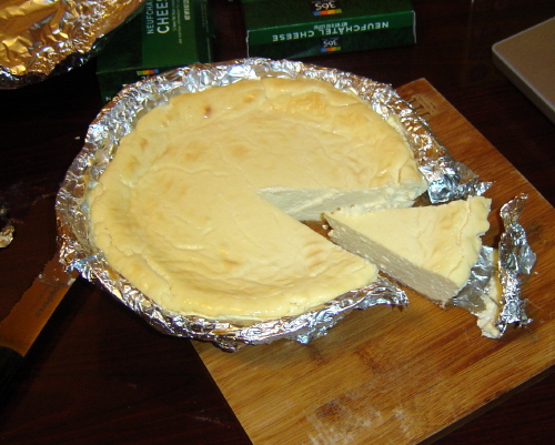 [finished cheesecake with one slice cut]